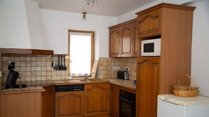 Une cuisine avec des meubles de rangement en bois, un four à micro-ondes, un grille-pain et un lave-vaisselle.