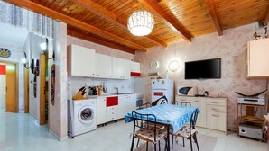 Une cuisine équipée d’un lave-linge, d’une table à manger avec des chaises et d’un téléviseur.