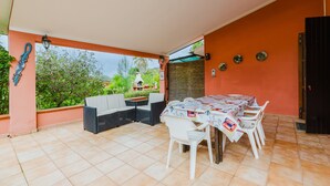 Une terrasse extérieure avec une table et des chaises, un canapé et un mur décoratif.