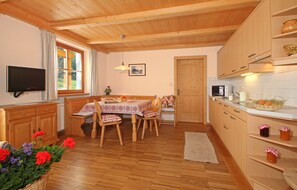 Un intérieur en bois comprenant une table à manger, des chaises, un téléviseur et des appareils de cuisine.