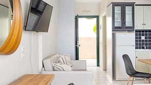 A modern kitchen with a refrigerator, cabinets, and a dining area with a table and chairs. - Apartment in a Hotel 'Sunset Premium Studio A' with Sea View, Shared Pool, & Wi-Fi (Lefkada)