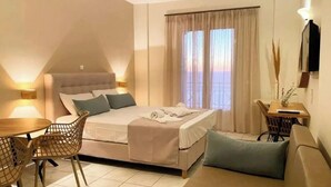 A bedroom with a bed, a sofa, a dining table, and chairs. - Apartment 'Sunset Premium Studio B' with Sea View, Shared Pool & Wi-Fi (Lefkada)