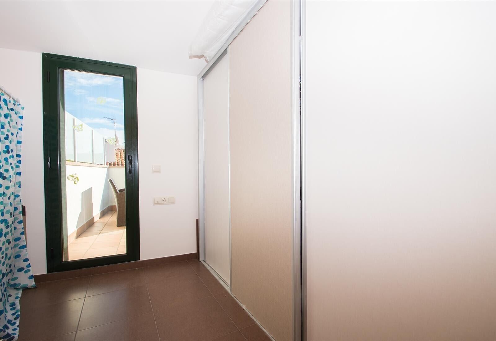 A hallway with a sliding door leading to an outdoor balcony.