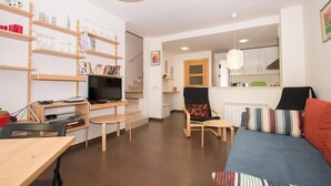 A living room with a TV, bookshelves, a sofa, and a dining area.