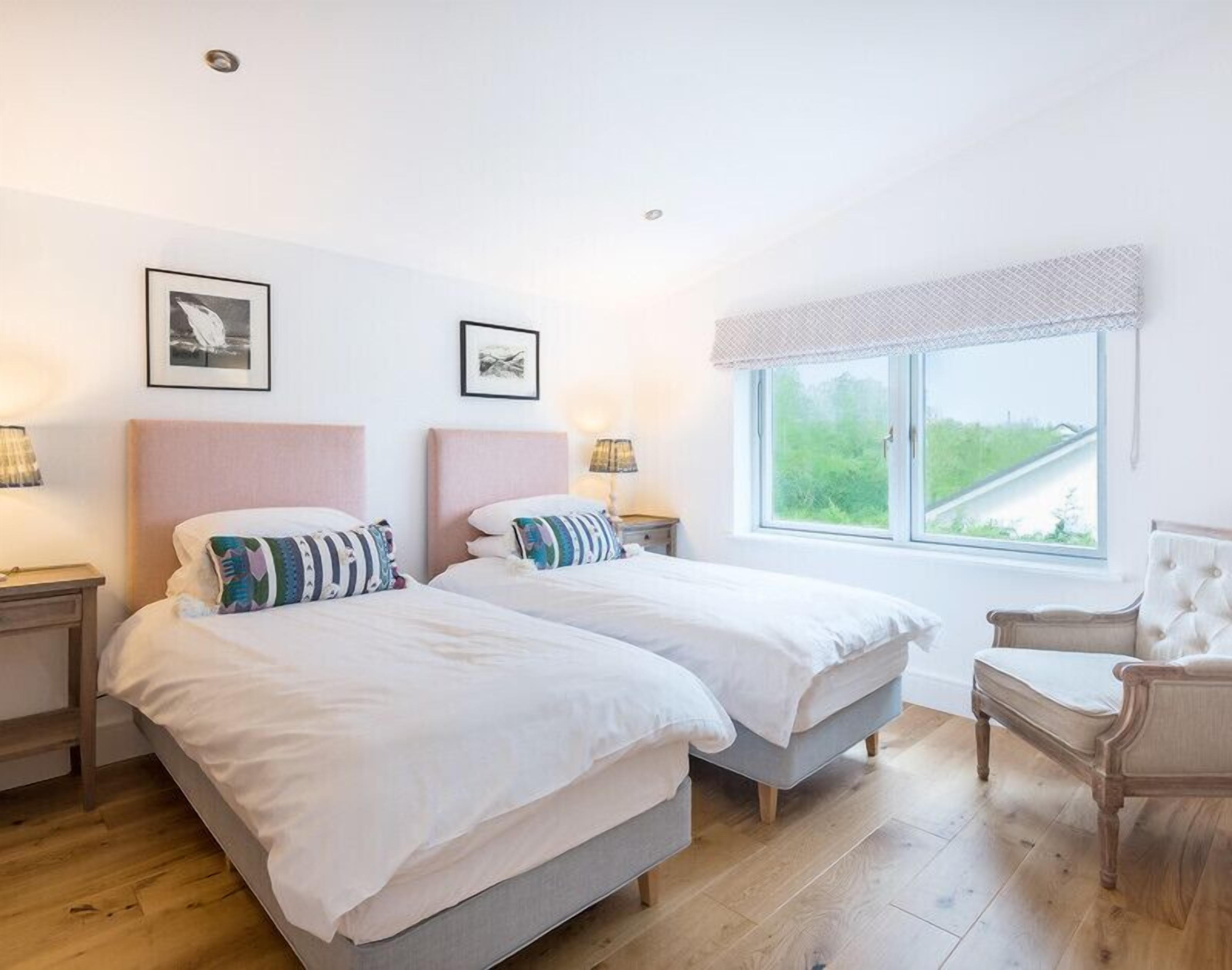 Une chambre double avec deux lits, une fenêtre donnant sur un beau paysage et une chaise.