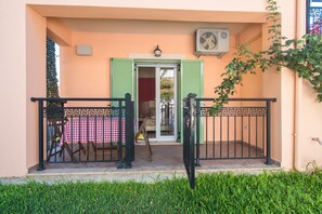Un balcon avec une table à carreaux, des volets verts et un ventilateur fixé au mur.