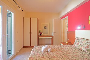 Une chambre à coucher avec un lit, une commode, un miroir et une porte.