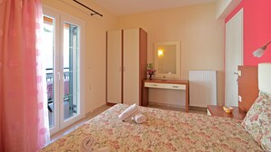 Un dormitorio con cama, cómoda, espejo y ventana con cortina.