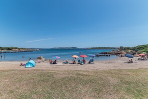 Una playa con gente, tiendas de campaña y sombrillas.