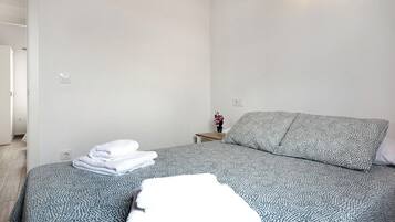 A bedroom with a bed, a nightstand, and a wall socket.