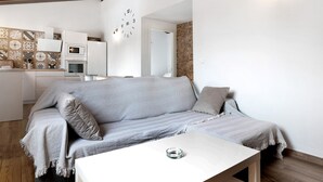 Un salon moderne avec un canapé, une table basse et un coin cuisine à l’arrière-plan.