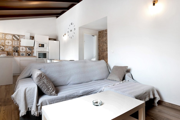 A modern living room with a sofa, a coffee table, and a kitchen area in the background.