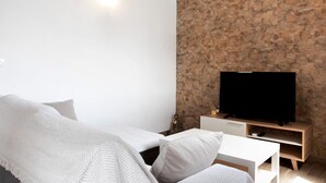 Une chambre à coucher moderne avec un lit, un téléviseur et un mur en pierre.