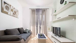 A modern living room with a sofa, a coffee table, a TV, and a window with curtains.