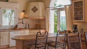 A kitchen with a large island, bar stools, and a view through the window. - Villa Lino with Mountain Views, Pool, Garden, and Wi-Fi (Benalup Casas Viejas)