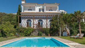 A large house with a swimming pool, a covered patio, and a staircase leading to the upper floors. - Villa Lino with Mountain Views, Pool, Garden, and Wi-Fi (Benalup Casas Viejas)