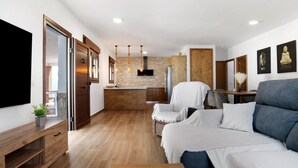 A modern living room with a sofa, TV, wooden cabinet, and a kitchen area in the background. - Holiday Home 'Casa La Teja 2' with Pool and Wi-Fi (Vejer de la frontera)