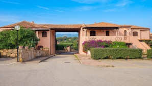 A building with a tiled roof, an archway entrance, and a paved driveway. - Casa Turisarda Apartment with Shared Pool, Terrace, and Air Conditioning (Baja Sardinia)