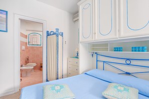 Ein Schlafzimmer mit Bett, Kleiderschrank, Badezimmer mit Toilette, Bidet und Duschbereich.