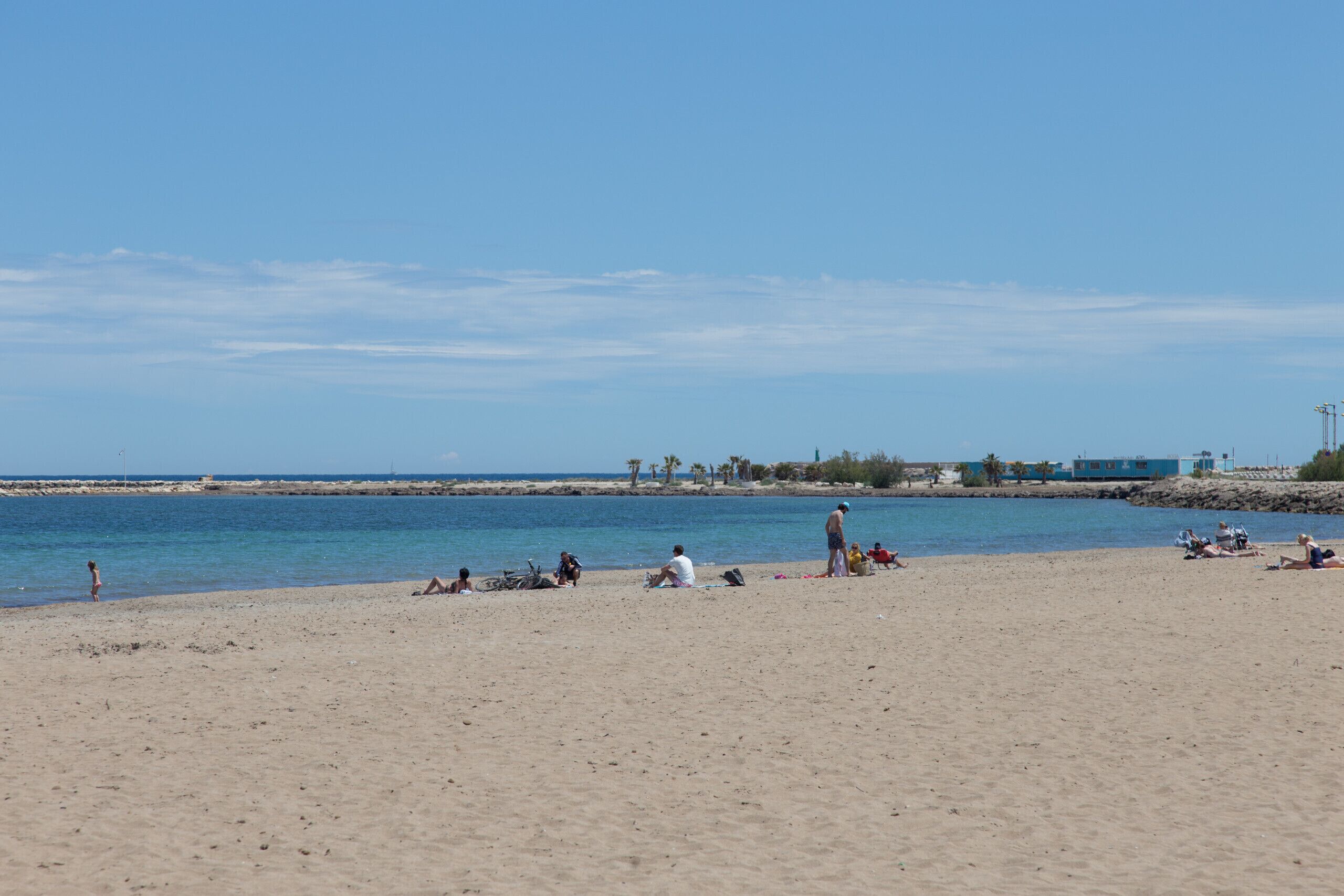 A beach with people relaxing and sunbathing.