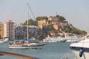 Boats docked in a picturesque marina, with a historic castle perched on a hill in the background.