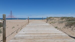 Une promenade en bois menant à une plage, avec un ciel dégagé.