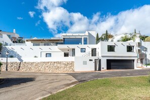 A modern multi-story residential building with a stone wall, a garage, and a clear blue sky. - Luxury Villa with Private Pool, with Sea View, Wi-Fi and Air Conditioning (La Cala de Mijas)