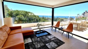 A modern living room with a sofa, chairs, a coffee table, and a view of the ocean. - Luxury Villa with Private Pool, with Sea View, Wi-Fi and Air Conditioning (La Cala de Mijas)