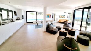 A modern interior with a kitchen, seating area, and large windows. - Luxury Villa with Private Pool, with Sea View, Wi-Fi and Air Conditioning (La Cala de Mijas)