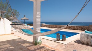 Una hamaca, una piscina y vista al océano.
