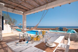 Um terraço com piscina, área de estar ao ar livre e vista para o mar.