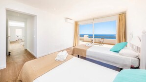 A hotel room with two beds, a balcony with a view of the sea, and a separate room visible through an open door. - Holiday Home Villa Domus Alba B with Sea View, Pool, Garden & Wi-Fi (portocolom)