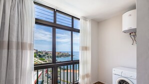 Un balcón con vistas a un pueblo costero, una lavadora y un calentador de agua.