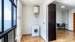 Un área de lavandería con lavadora, calentador de agua y comedor con mesa y sillas.