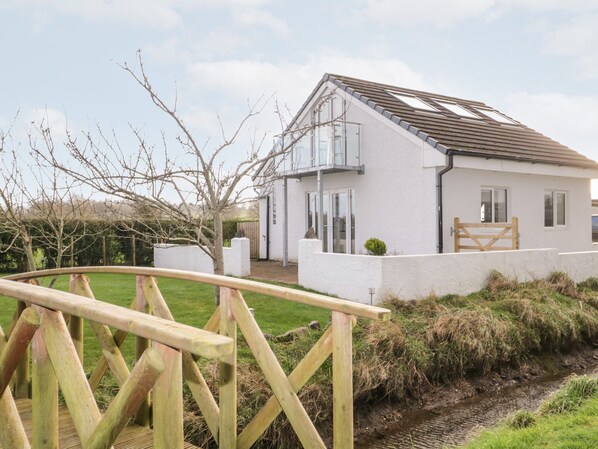 A white house with a sloped roof, a wooden gate, and a grassy yard. - The Annex (Ulverston)