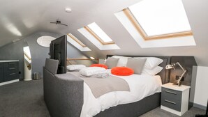 Ein modernes Schlafzimmer mit Dachfenster, einem Bett, einem Nachttisch und einem Kleiderschrank.