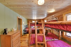 Eine Holzhütte mit Etagenbetten, Holzvertäfelung, einem Schminktisch und einem Fenster.