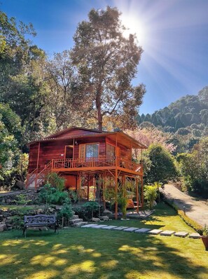 A wooden cabin with a balcony, surrounded by a well-maintained garden and a stone pathway. - Friedenstal Resort (Nainital)