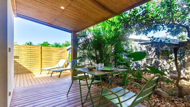 An outdoor patio with a wooden deck, metal chairs, and a table. - Bungalow (Saint Paul)
