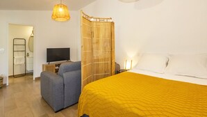 A bedroom with a bed, a sofa, a television, and a bamboo partition. - Bungalow (Saint Paul)