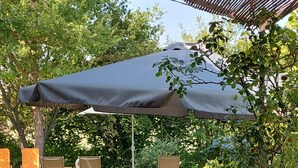An outdoor patio with wicker furniture, a pool, and a covered area with a large umbrella.