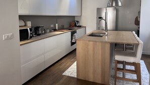 A modern kitchen with white cabinets, a wooden island, and a stainless steel sink. - Pleasant town house on the outskirts of Paris (Nanterre)