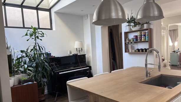 A modern kitchen with a central island, a piano, and potted plants. - Pleasant town house on the outskirts of Paris (Nanterre)
