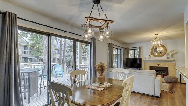 A spacious living area with a wooden dining table, white chairs, a fireplace, and a television.