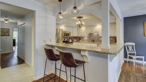 A modern kitchen with a large island, bar stools, and pendant lighting.
