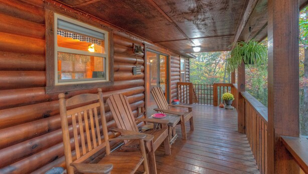 A wooden log cabin with a porch featuring wooden chairs and a table, a potted plant, and a view of trees. - ☆Augst Week Day Openings☆ 
 (Murphy)