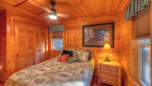 A cozy wooden cabin bedroom with a bed, a nightstand, a lamp, a framed picture, and a window. - ☆Augst Week Day Openings☆ 
 (Murphy)