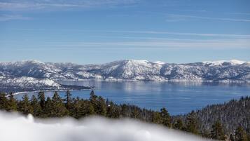 Une vue panoramique d’une chaîne de montagnes enneigées, avec un lac au premier plan.