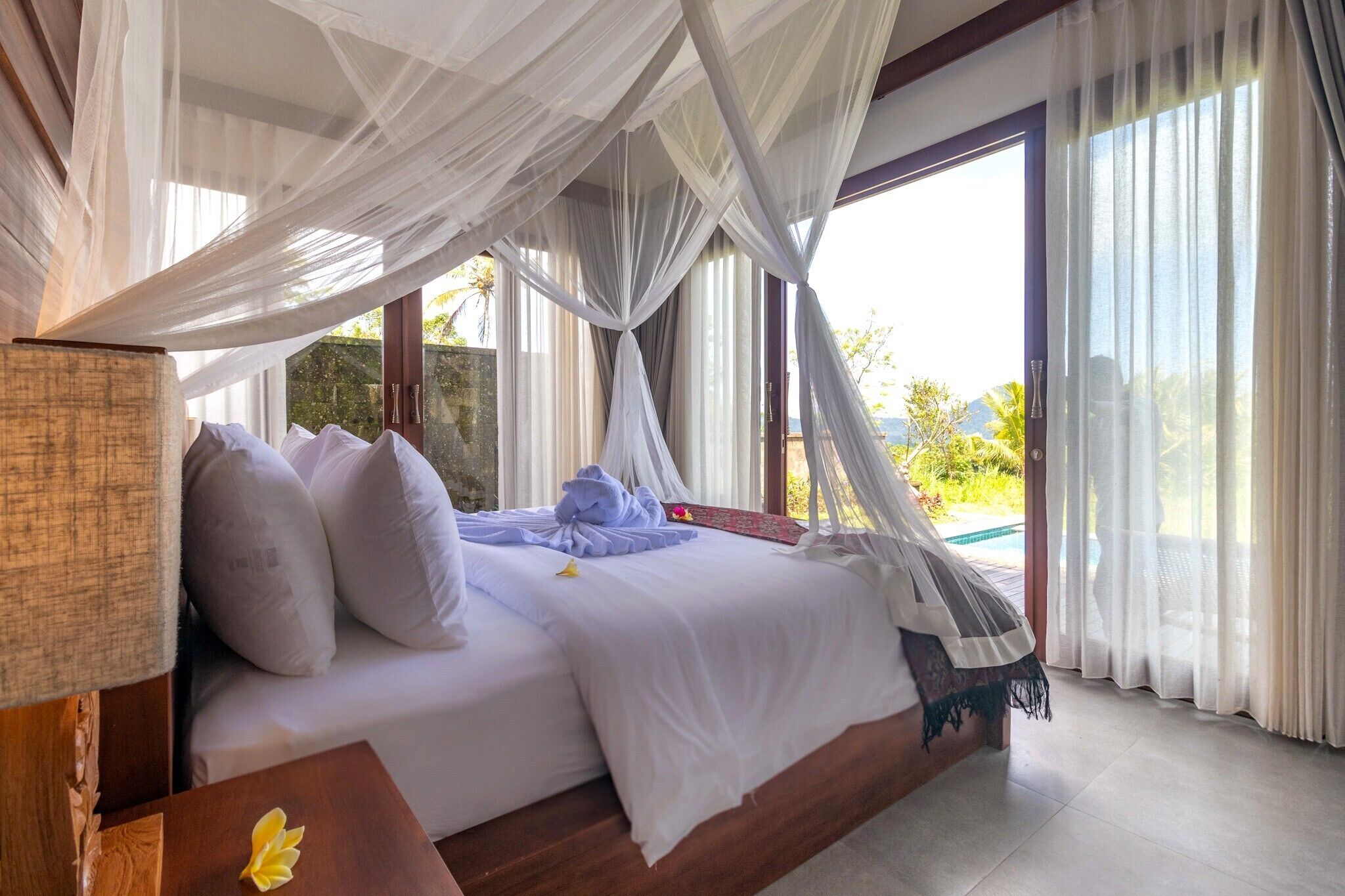 Un dormitorio con cama con dosel, vistas al exterior y una piscina.