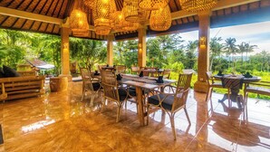 Un espacio de comedor al aire libre con mobiliario de bambú e iluminación tejida.